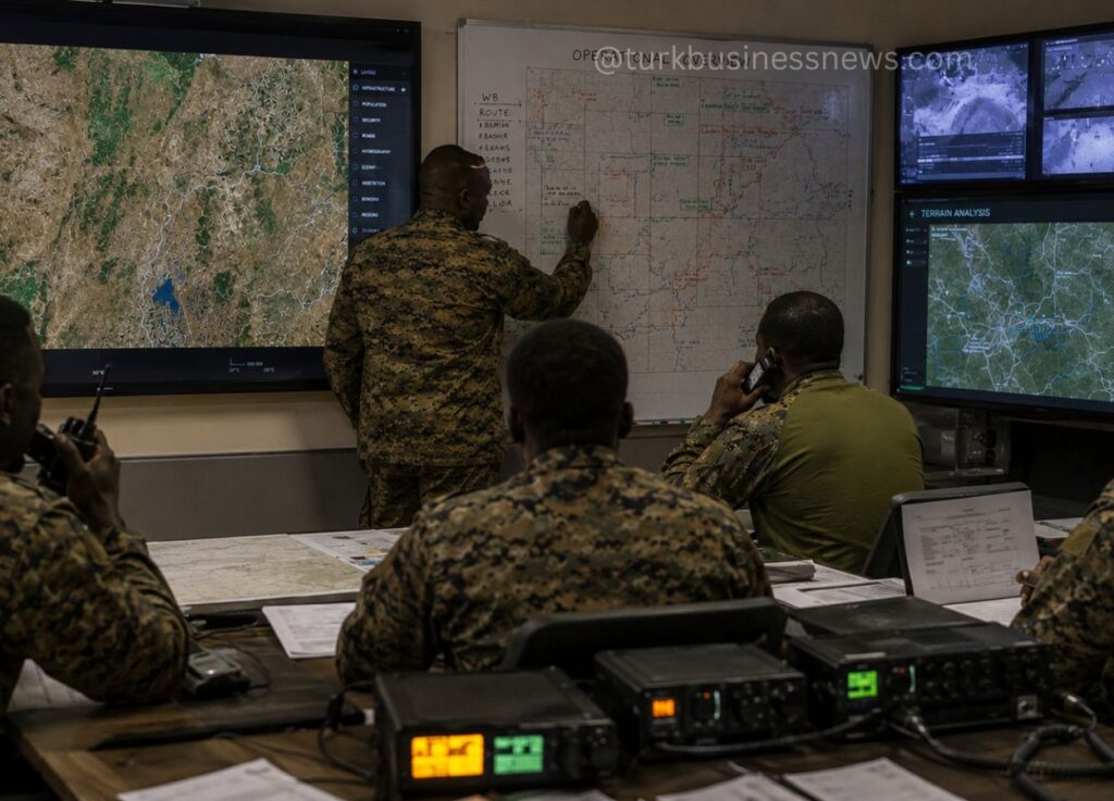 40 - Military personnel in camo work in a command center, studying a large map on a whiteboard and satellite screens displaying terrain data and routes.